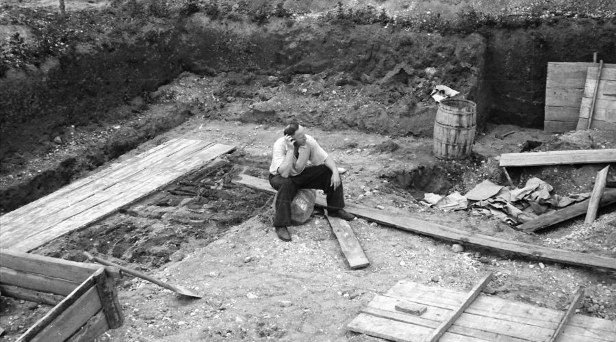 Nespalvota nuotrauka sėdi žmogus statybų aikštelėje